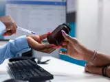 Provider handing a patient a prescription bottle across a desk